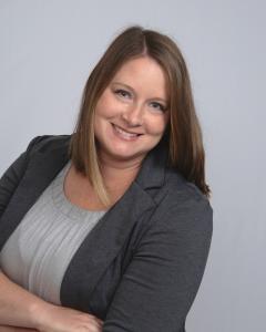 Picture of a woman in a grey shirt with a dark grey suit jacket